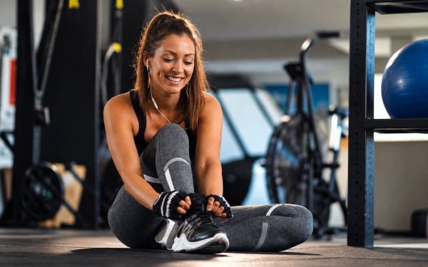 Mulher ajustando o tênis esportivo durante treino em academia